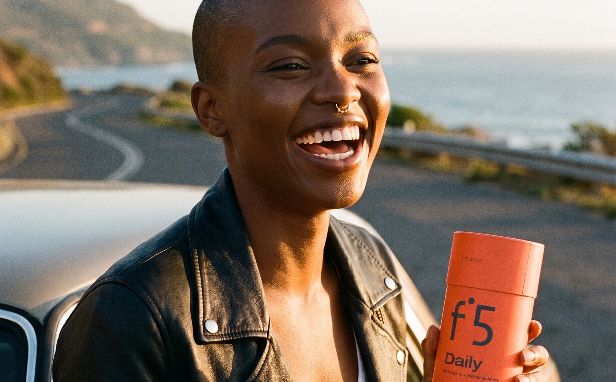 Woman on a coastal road holding the f°5 Daily tube and two gummies