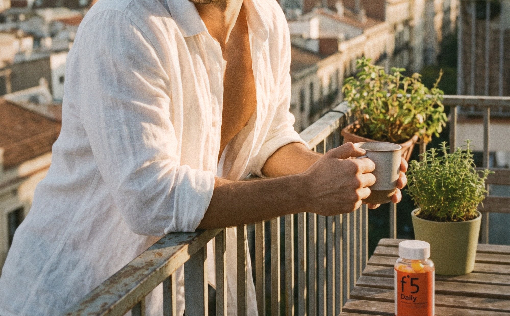 Young man on a balcony at sunrise, the f°5 Daily jar on the table
