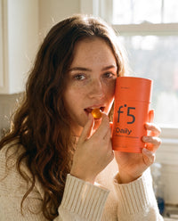 Woman eating an f°5 Daily gummy, holding the tube
